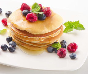 Sweet pancakes with raspberries and blueberies on  white plate