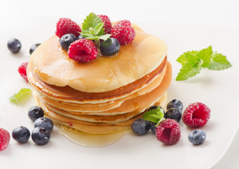 pancakes with raspberries and blueberies on a white plate