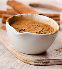 Cinnamon sticks and meal  on wooden board.