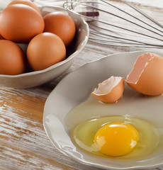 Broken raw brown egg on a wooden background