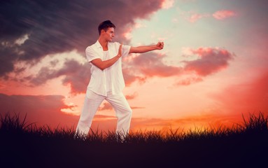 Fototapeta na wymiar Composite image of handsome man in white doing tai chi