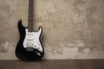 Black guitar near the wall