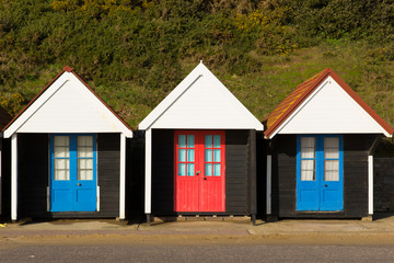 Fototapeta na wymiar Three colourful beach huts with blue and red doors in a row