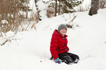 Fototapeta na wymiar A boy sliding down a hill in snowy landscape
