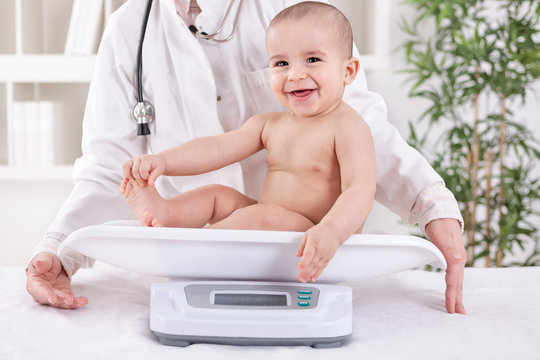 Happy smiling baby in pedrician office, measuring weight
