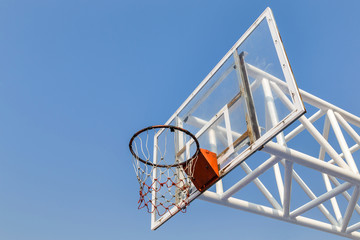 glass basketball board with  yellow hoop on blue sky background