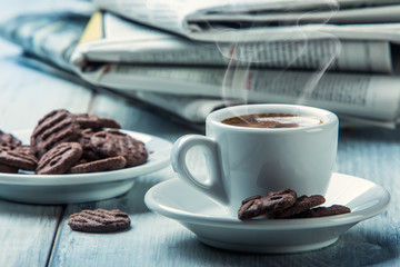 Cup of coffee , chocolate biscuits and the background newspaper