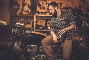 Man and vintage style cafe-racer motorcycle in garage