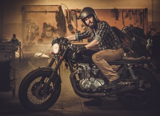 Man and vintage style cafe-racer motorcycle in garage