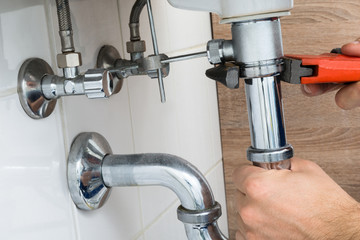 Male Plumber Fixing Sink In Bathroom