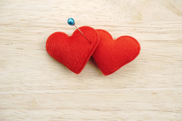 two red hearts pinned on wooden background