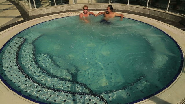 Couple relaxing together on a jacuzzi pool at spa.