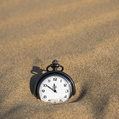 Pocket watch buried in sand