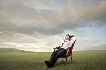 Fototapeta na wymiar Relaxed businessman in a meadow