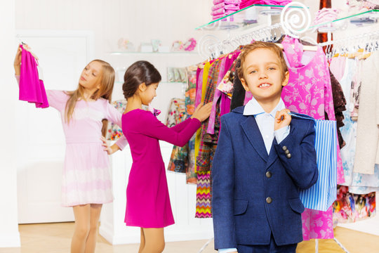 One boy with shopping bag and girls choose clothes