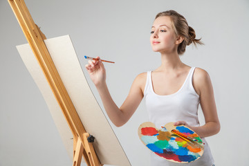 Girl paints on canvas with oil colors over white