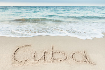 Fototapeta na wymiar Cuba Written On Sand By Sea