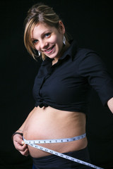A pregnant woman measuring her belly over white background