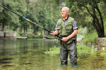 Cheerful mature fisherman fishing in a river