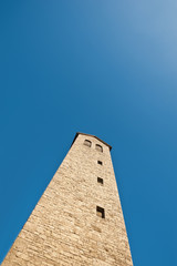 Ein eckiger Turm mit Satteldach unter blauem Himmel