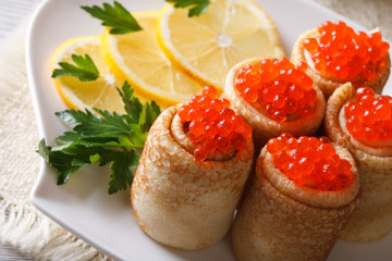 Rolls of crepe with red caviar on a plate closeup horizontal