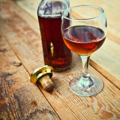 bottle and glass of cognac with ice on a wooden background