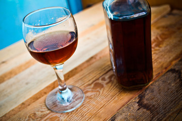 bottle and glass of cognac with ice on a wooden background