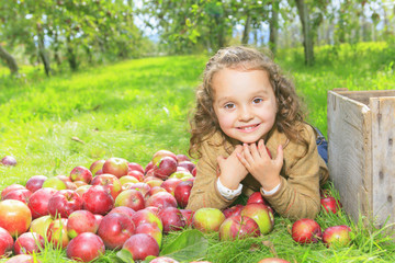 Cute little preschooler girl eating an apple on beautiful autumn