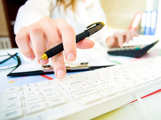 Woman with beautiful hands working on the calculator and keyboar