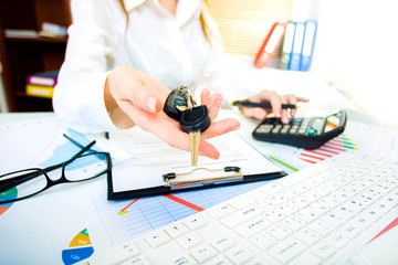 A woman's hand holds car keys and electronic door unlock in offi