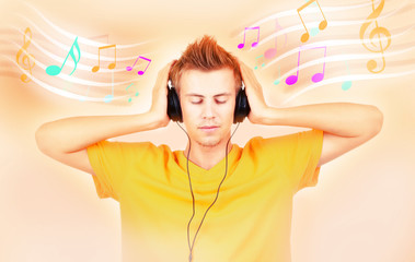 Young man with headphones listening music on bright background