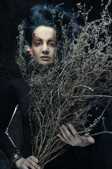 woman with bright make up with dry branches