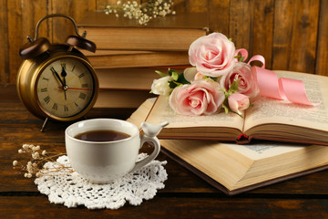 Cup of tea with books and flowers on wooden background