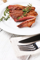 Steak with herbs on plate on wooden table