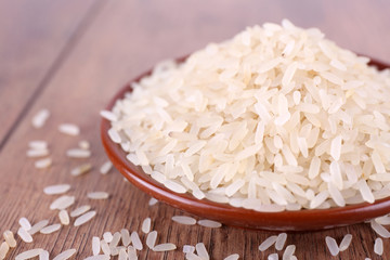 Grain of rice on plate on wooden background