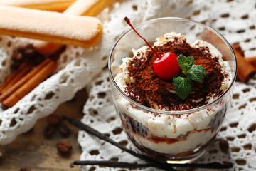 Tasty tiramisu dessert in glass, on napkin, on wooden