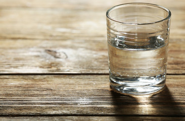 Glass of clean mineral water on rustic wooden planks background
