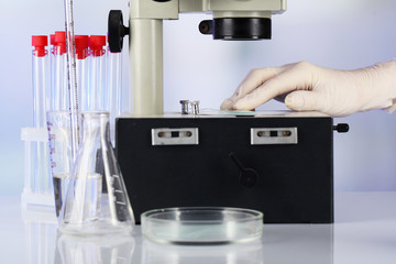 Hand of assistant in gloves working with microscope near test