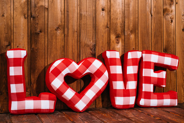 Love word of plush red letters on wood background. Full plaid