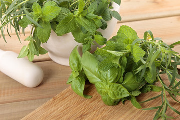 Fresh herbs with a mortar and pestle on a wooden worktop