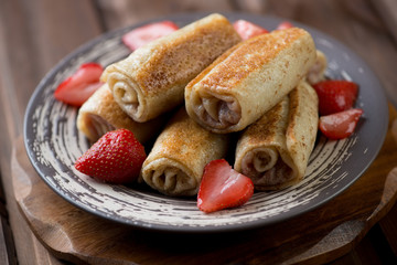 Rolled crepes with strawberry stuffing on a plate, studio shot