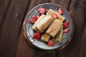 Pancakes with strawberry stuffing on a dark wooden background