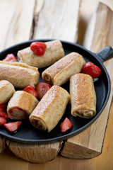 Pancakes with strawberry stuffing in a pan on firewood, close-up