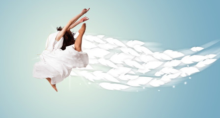 Fototapeta premium Healthy young woman jumping with feathers around her