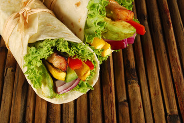 Chicken and avocado wrap sandwiches on wooden woven mat