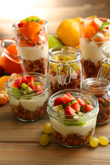 Healthy layered desserts with muesli and fruits on table