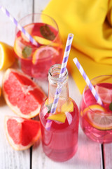Pink lemonade in glasses and bottle on table close-up