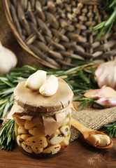 Canned garlic in glass jar, wicker mat and rosemary branches