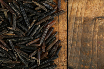 grains of black rice on wooden background