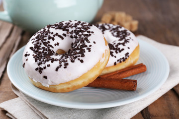 Delicious donuts with icing on plate on table close up